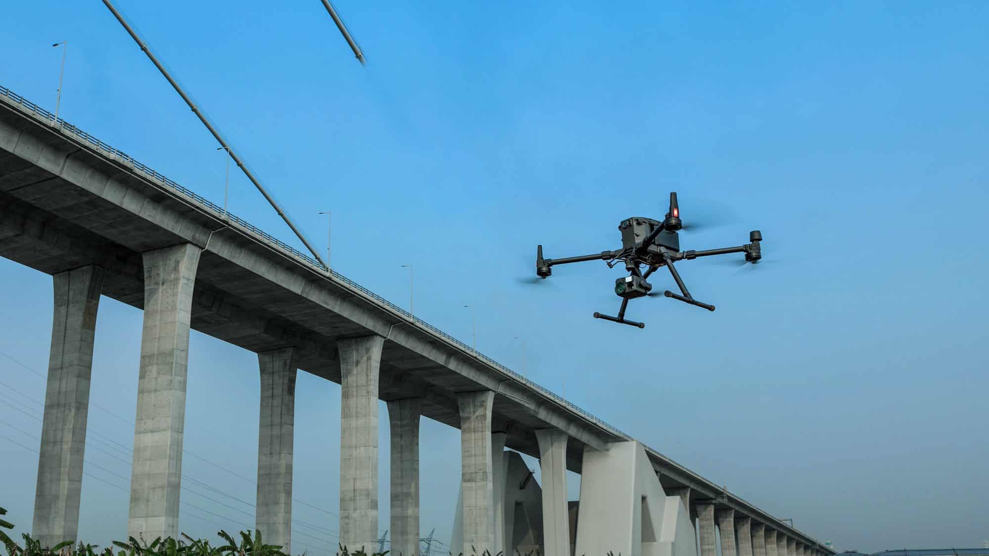 DJI Matrice 300 RTK inspecting a long concrete viaduct from the air.