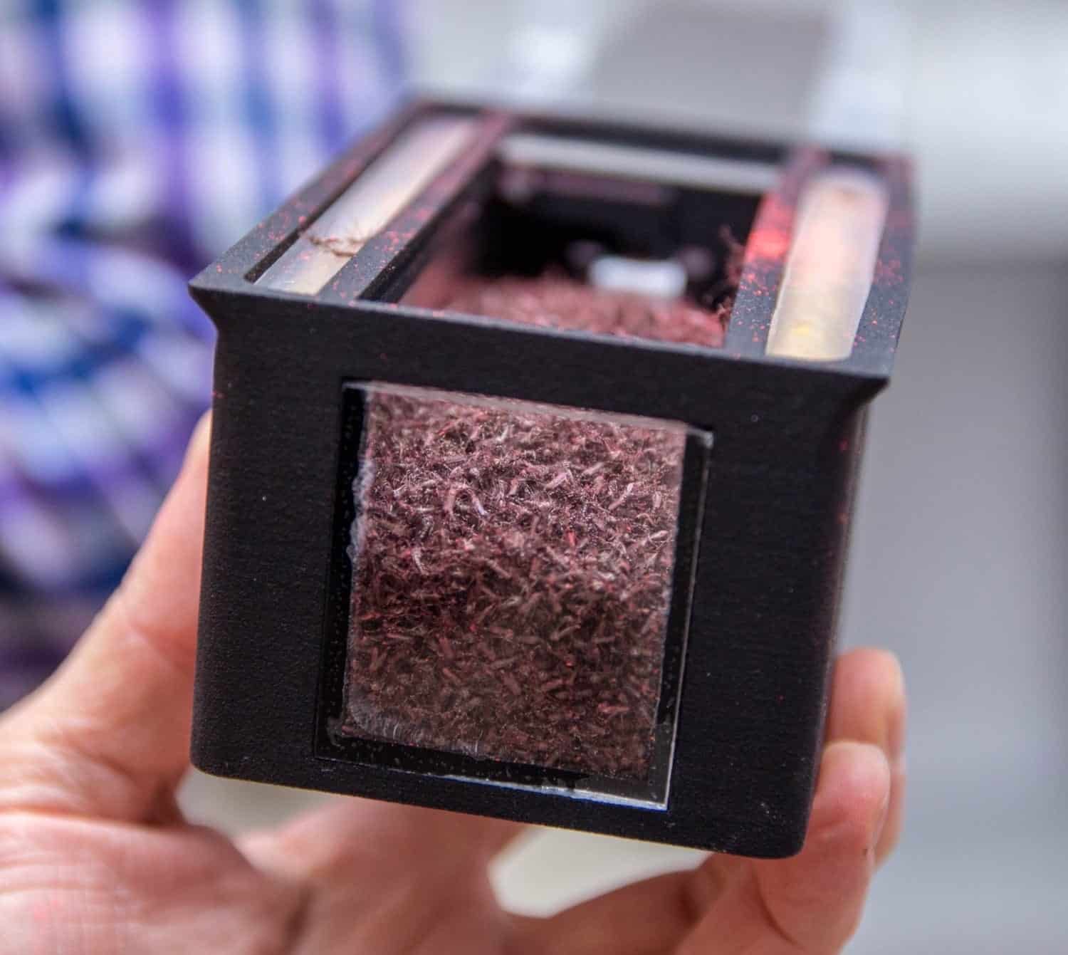 Hand holds an open cartridge packed with sterile mosquitoes for aerial release.