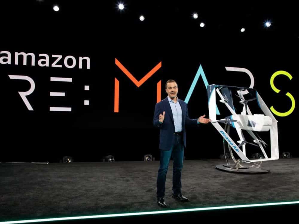 A presenter introduces the Amazon Prime Air delivery drone on the re:MARS stage.
