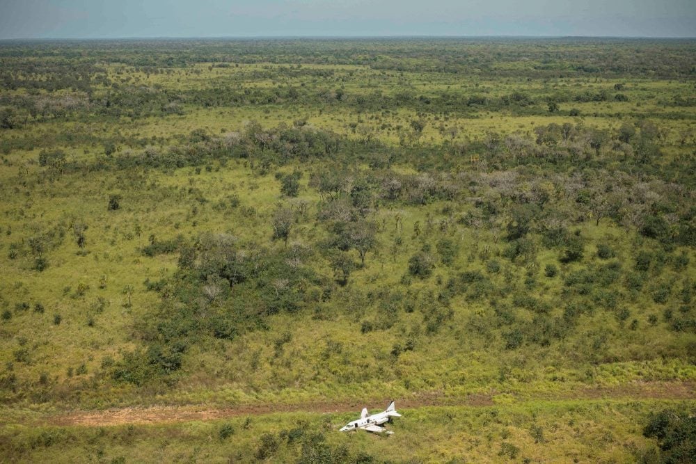 Aerial view of a small abandoned aircraft on a clearing in dense rainforest.