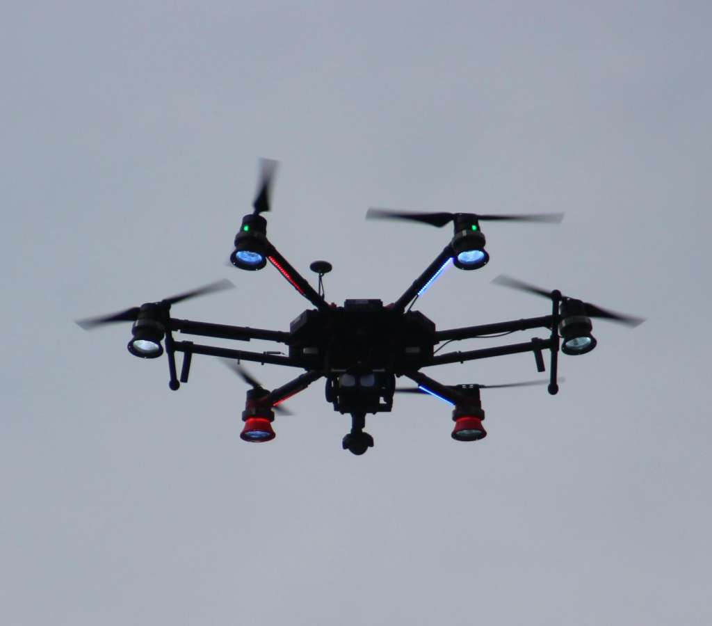 Black hexacopter with illuminated motor arms photographed against a plain background.