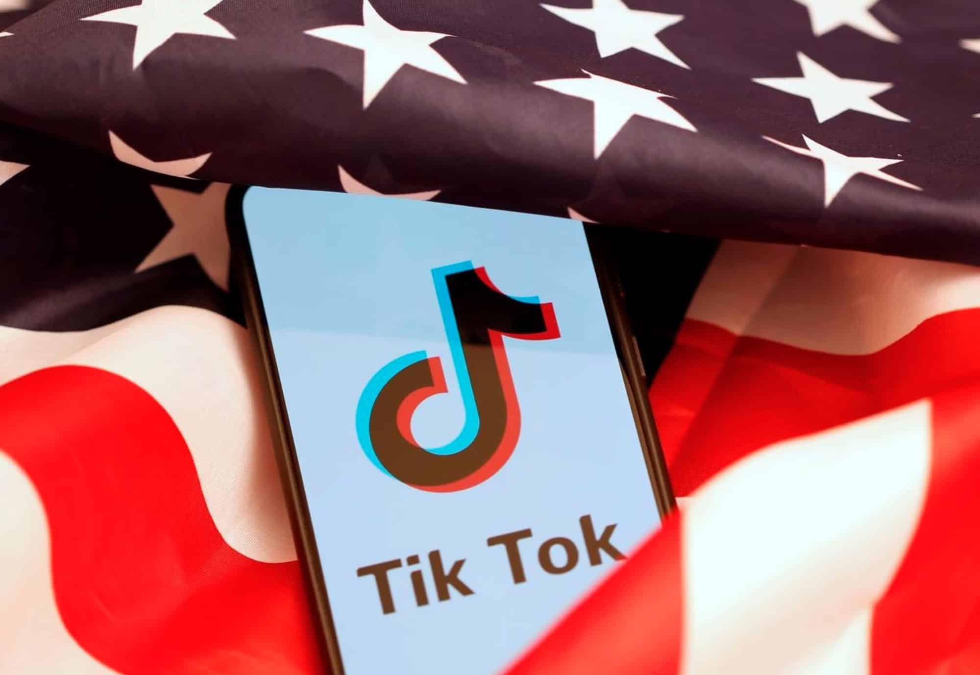 A smartphone displaying the TikTok logo resting on a United States flag.