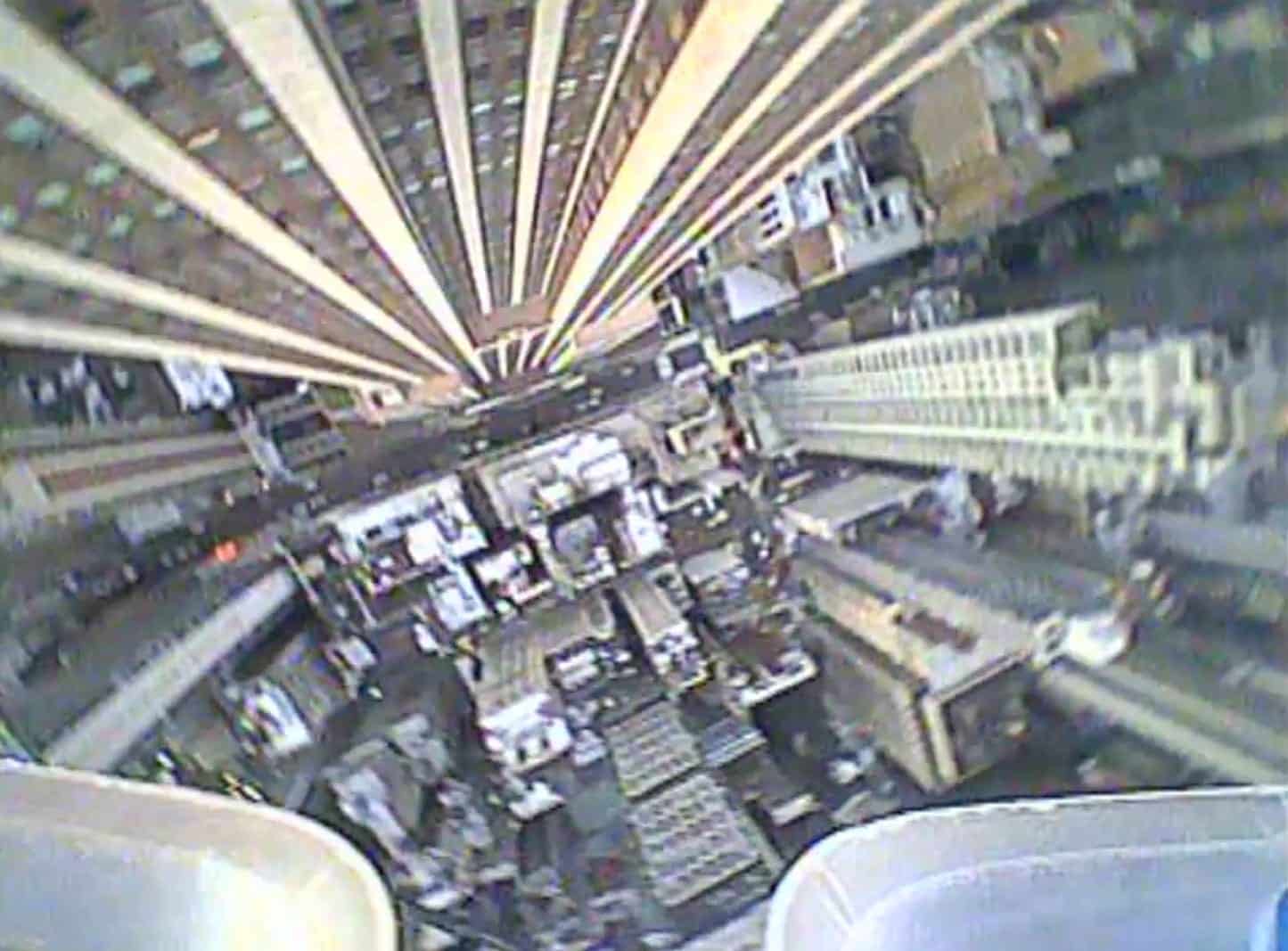 Straight-down drone view of a street canyon between converging skyscraper facades.