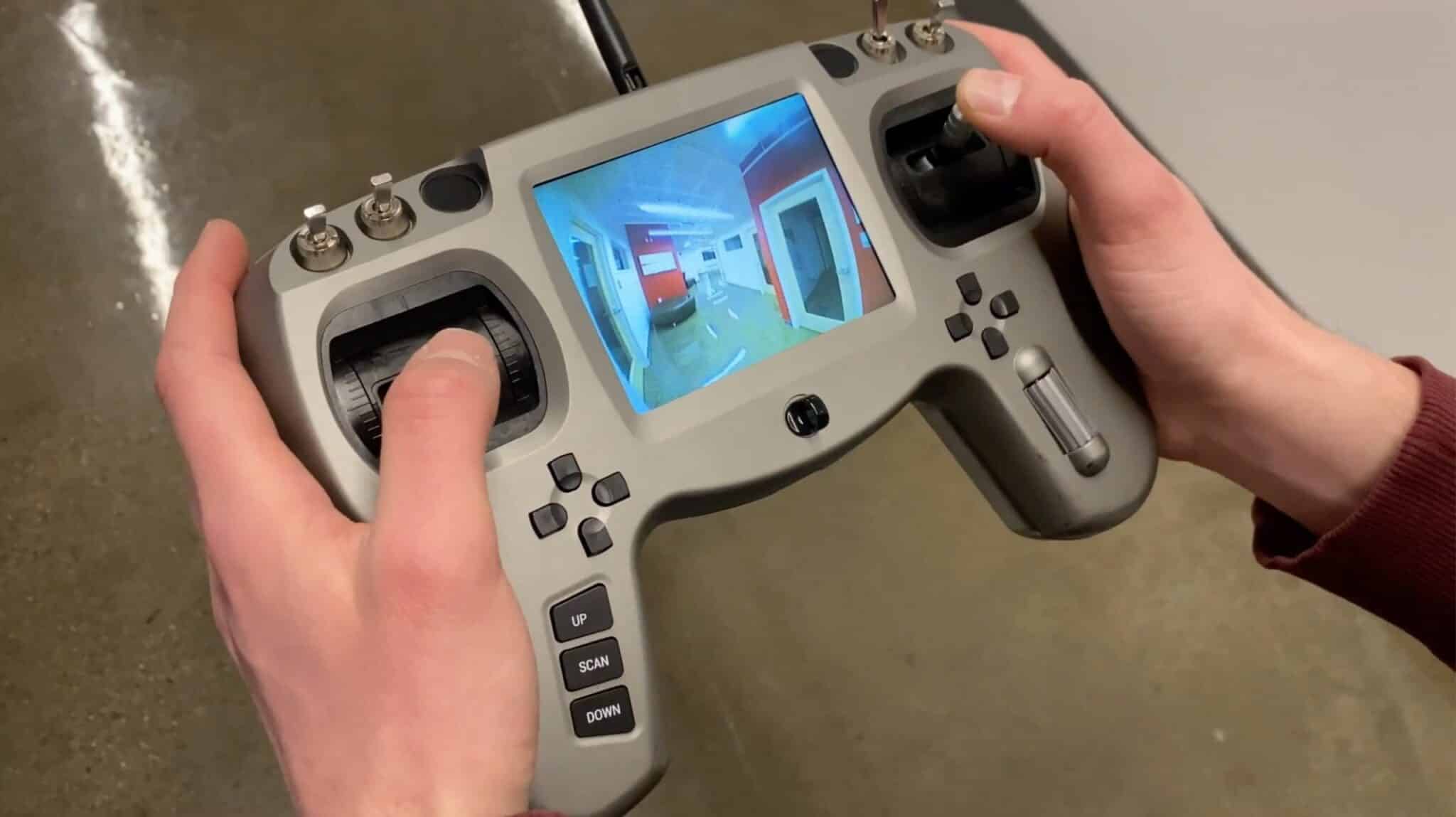 Hands holding the Dronut ground controller showing a live indoor camera view.