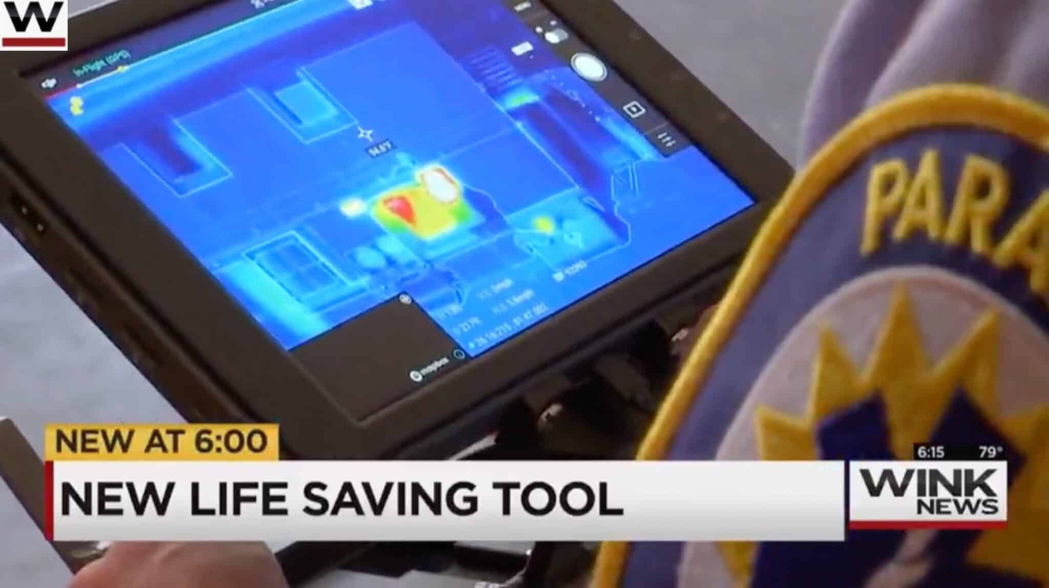 Local news footage of a firefighter viewing thermal drone imagery on a tablet.