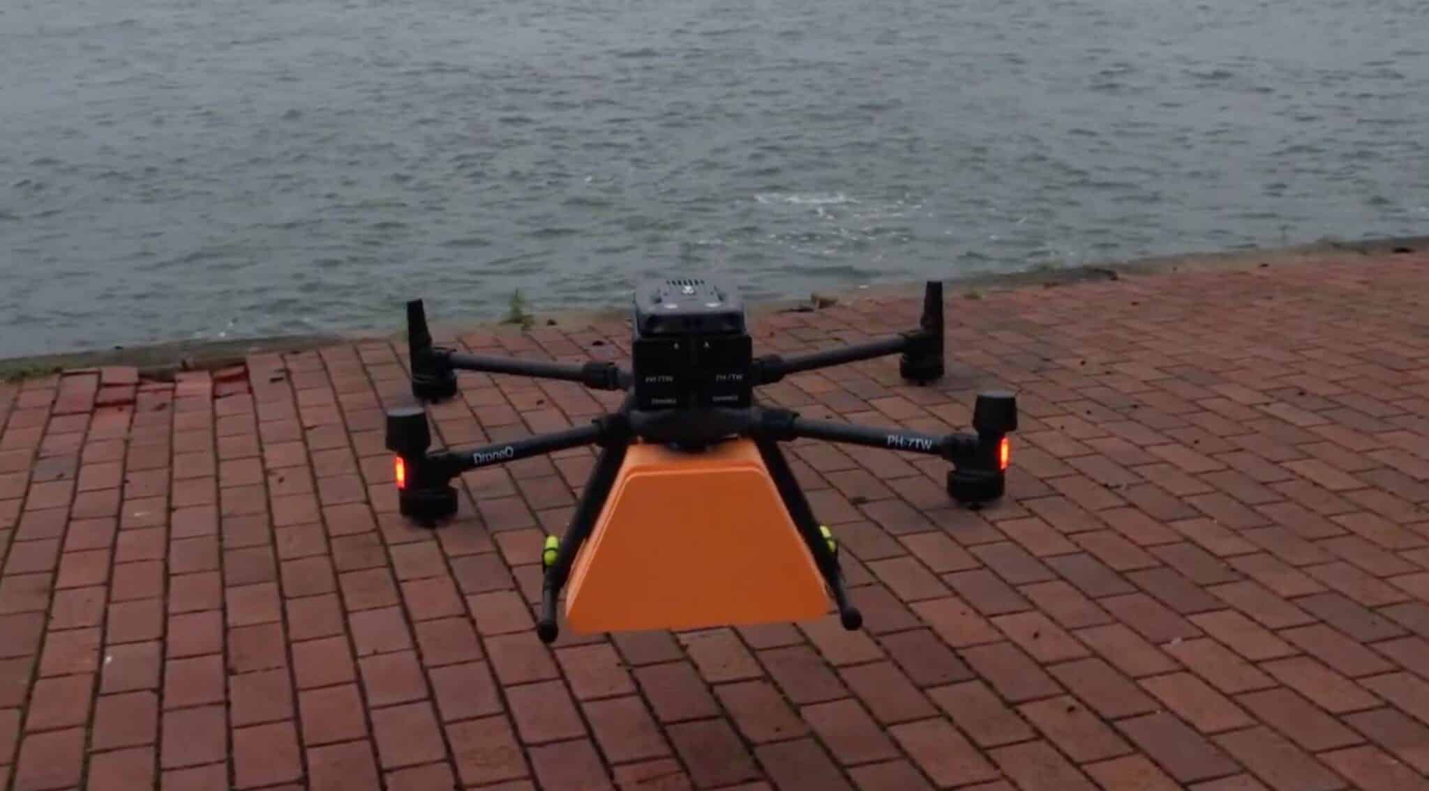 DJI Matrice 300 with an orange parcel box landing on a brick quay.
