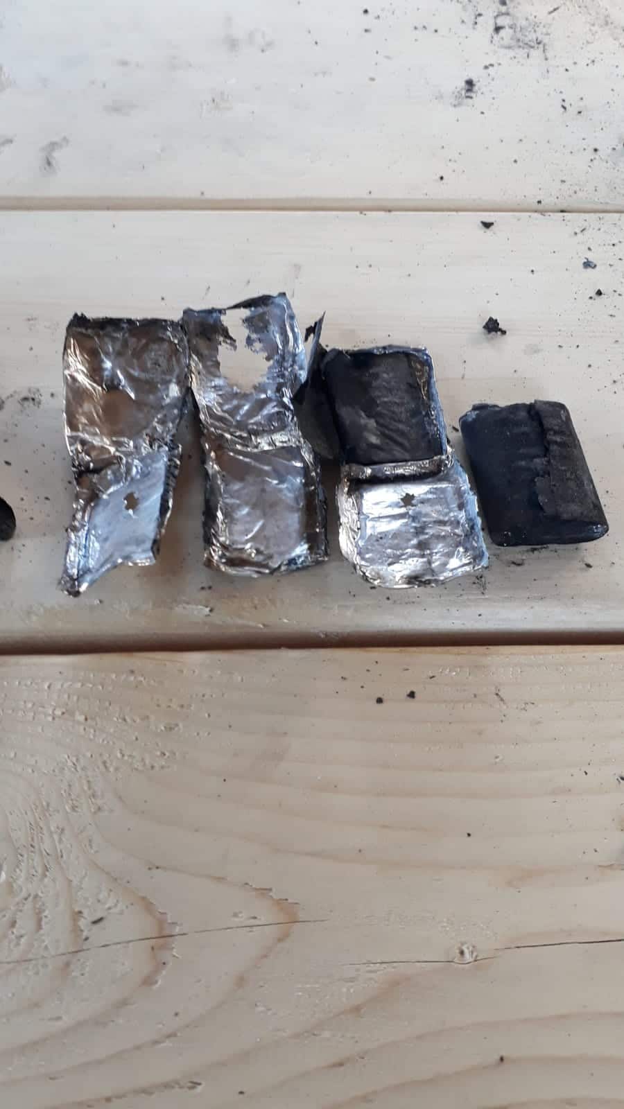 Four scorched lithium cells from the Mavic 2 Pro battery laid on a bench.