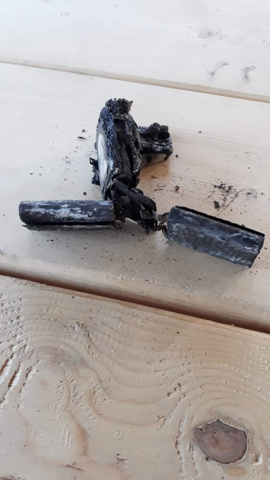 Two blackened, split battery cells left standing after the post-crash fire.