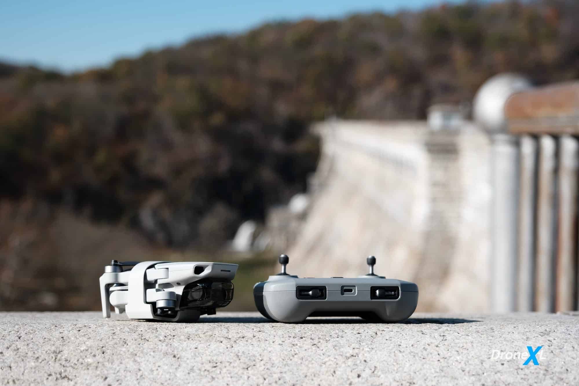 Folded DJI Mini 2 and its remote controller resting on a concrete ledge outdoors.