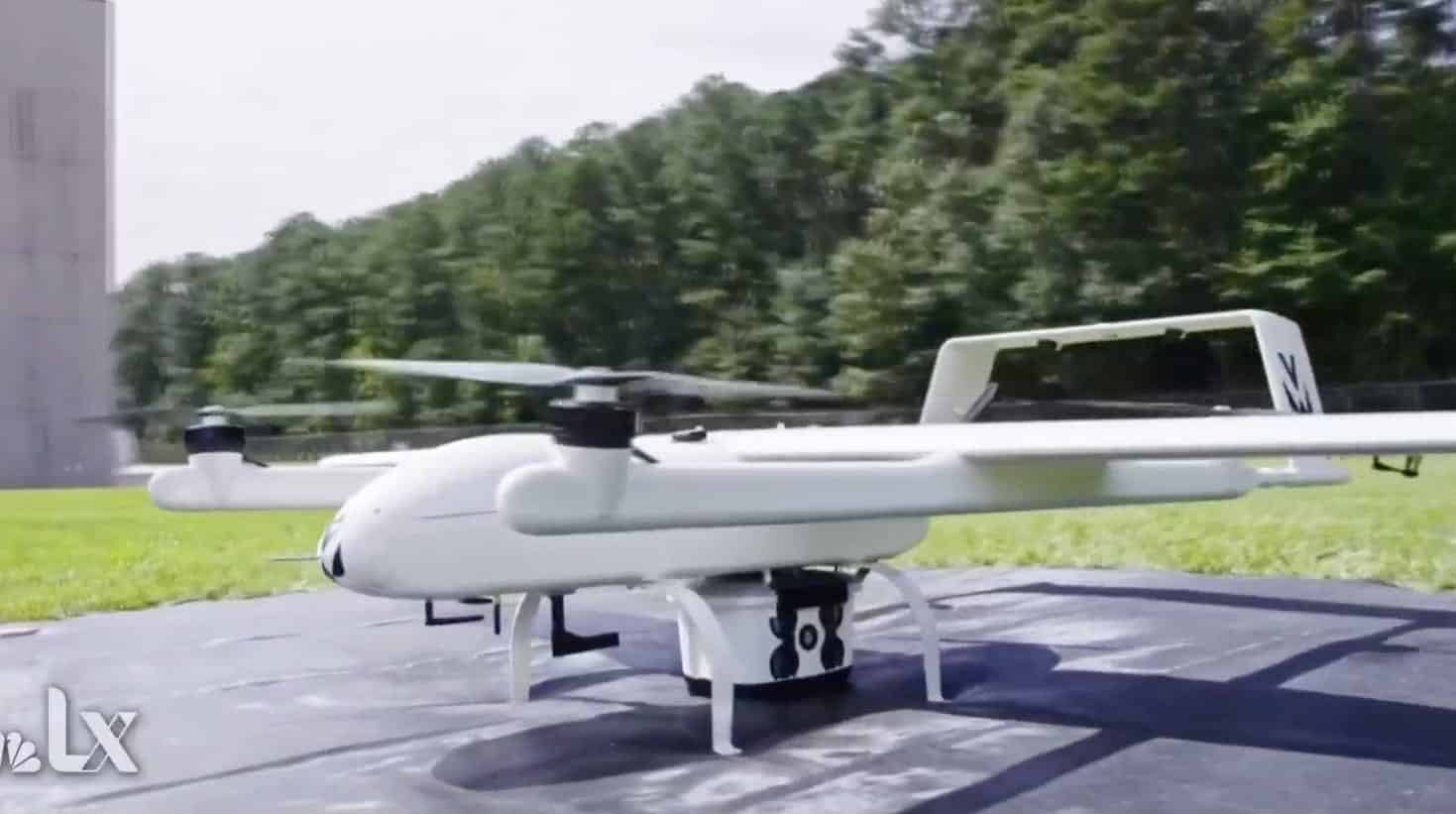 Volansi delivery drone sitting on a landing pad beside a rural tree line.
