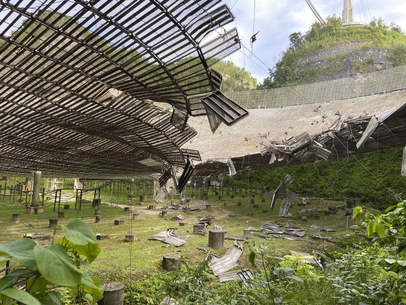 Torn reflector panels and debris hanging beneath the Arecibo dish.