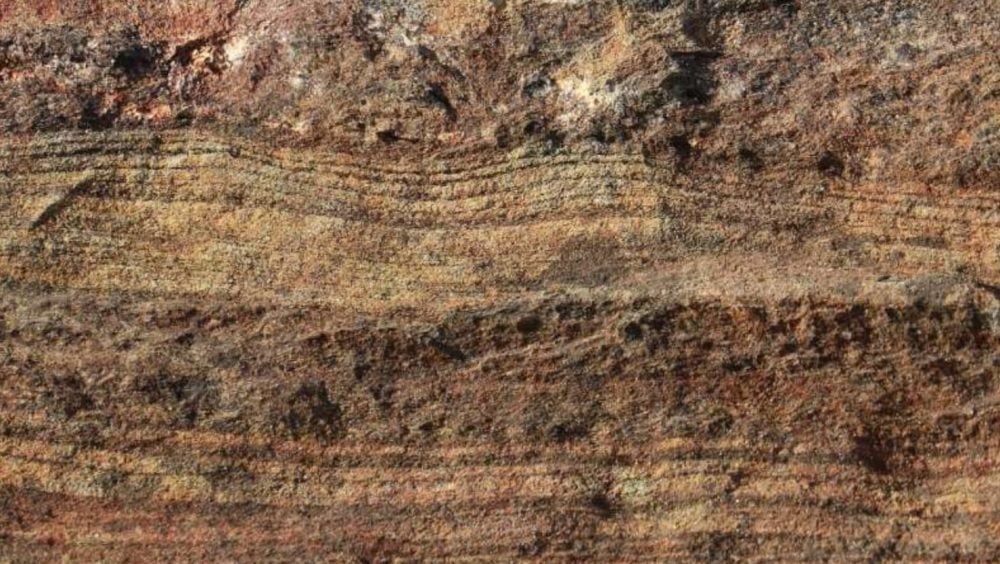 Close-up of layered sandstone strata in reddish and ochre bands.