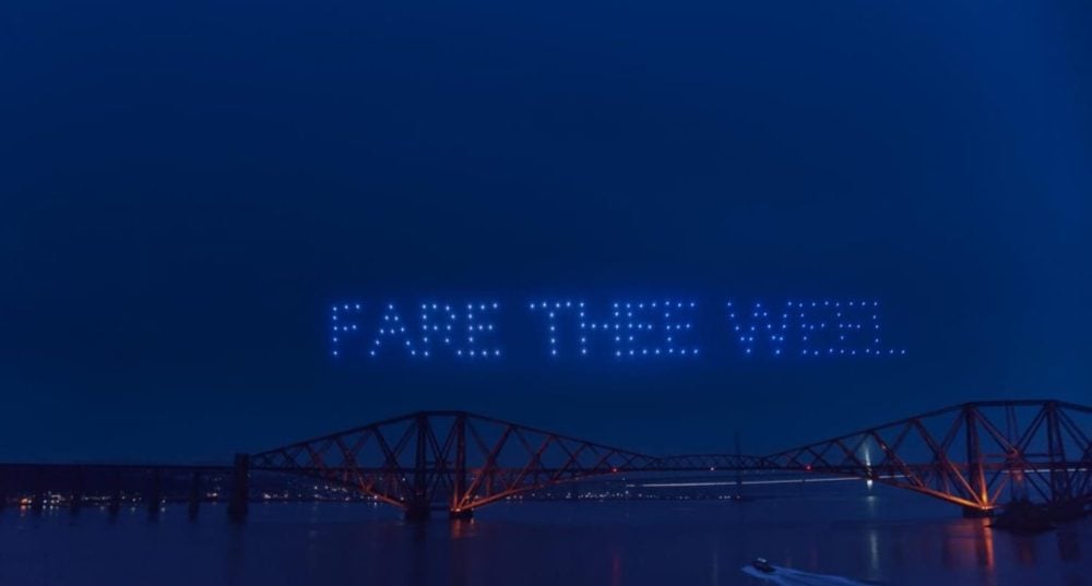 Drone light show spelling FARE THEE WEEL in the night sky above the Forth Bridge.