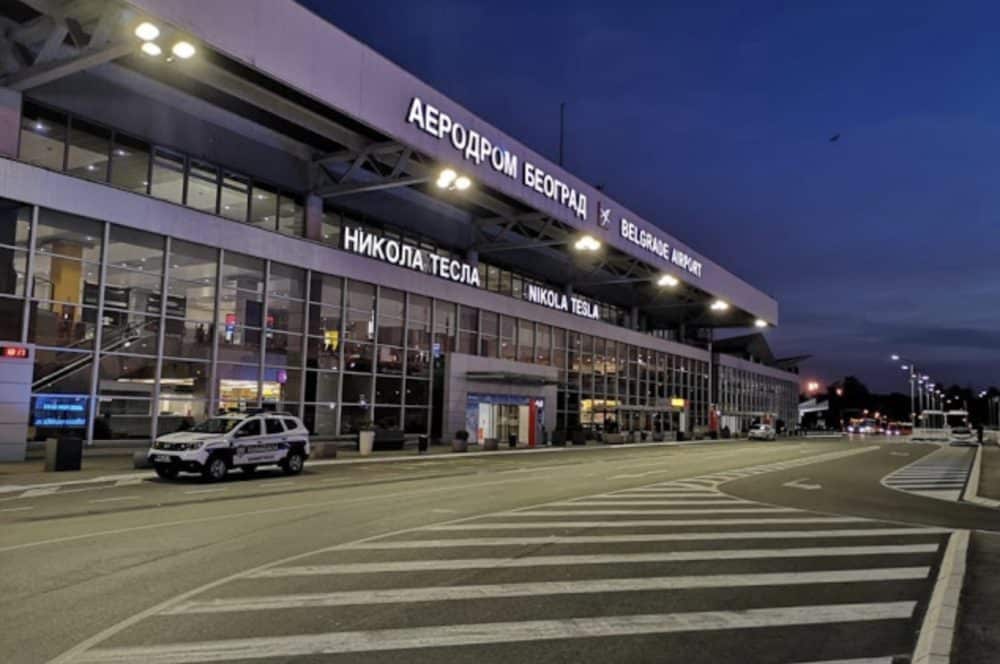 Belgrade Nikola Tesla Airport terminal exterior at dusk with an empty roadway out front.