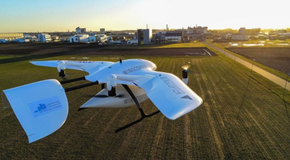 Two Wingcopter delivery aircraft parked on a grass airfield at sunset.
