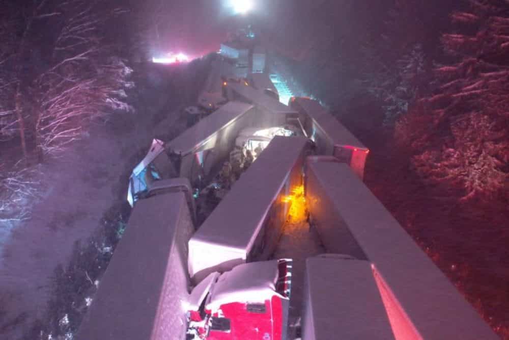 Night aerial view of snow-covered semi trucks jammed together after a highway pileup.