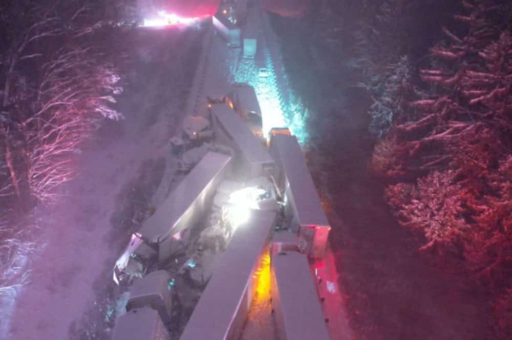 Night aerial of a multi-vehicle pileup with emergency lights across the highway.