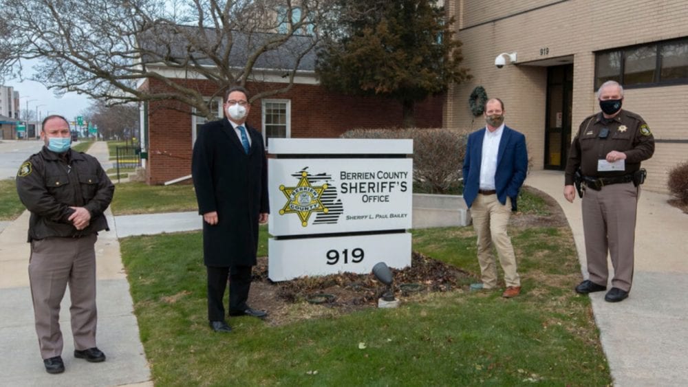 Masked officials stand by the Berrien County Sheriff's Office sign during a donation handover.
