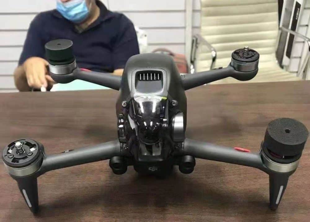 Leaked close-up of the unreleased DJI FPV drone on a table, arms extended forward.