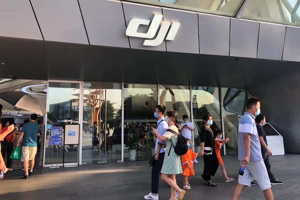 Shoppers in face masks walk past the entrance of a DJI flagship store.