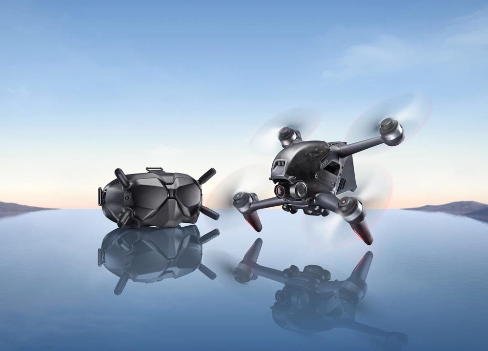 The DJI FPV drone and its goggles on a mirrored surface at dusk.