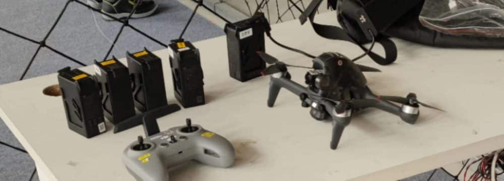 A test bench of charging batteries with the FPV drone and controller in front.