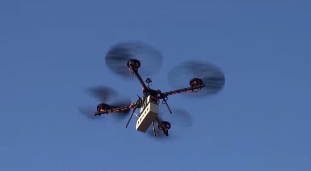 A quadcopter with oversized low-noise propellers flying against a clear blue sky.
