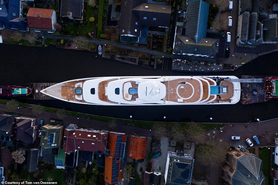 Bystanders watching from a bridge as the superyacht slips past.
