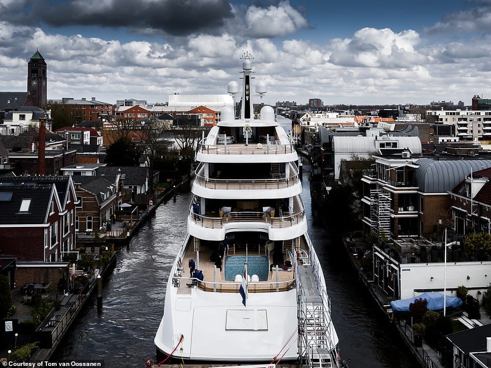 Feadship's Project 817 hull passing houses that line the waterway.