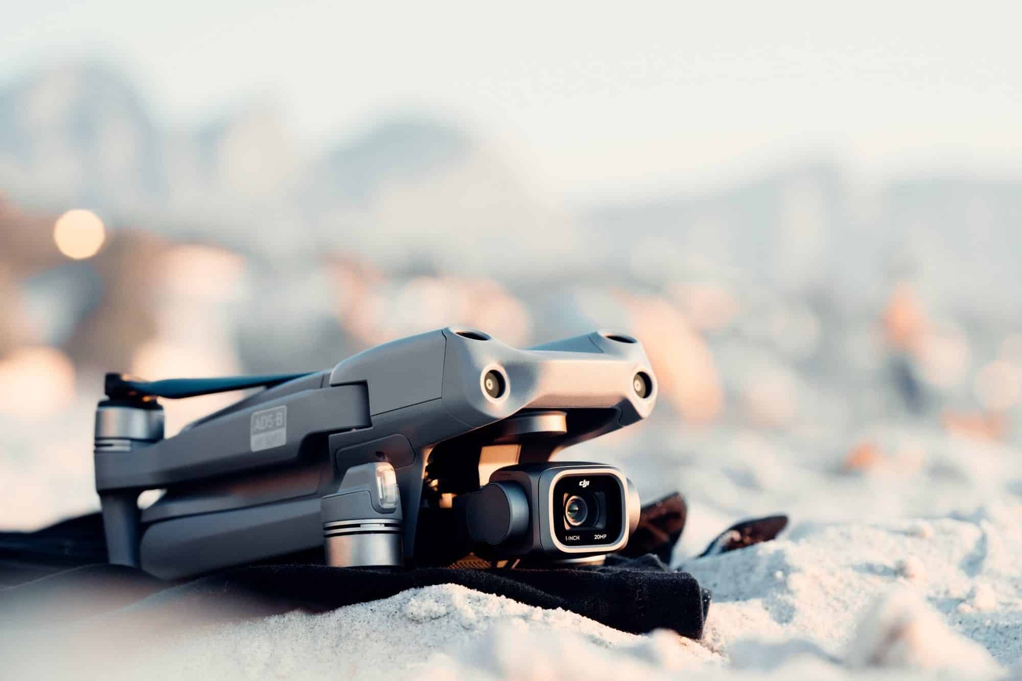 A folded DJI Air 2S sits on beach sand during golden hour.