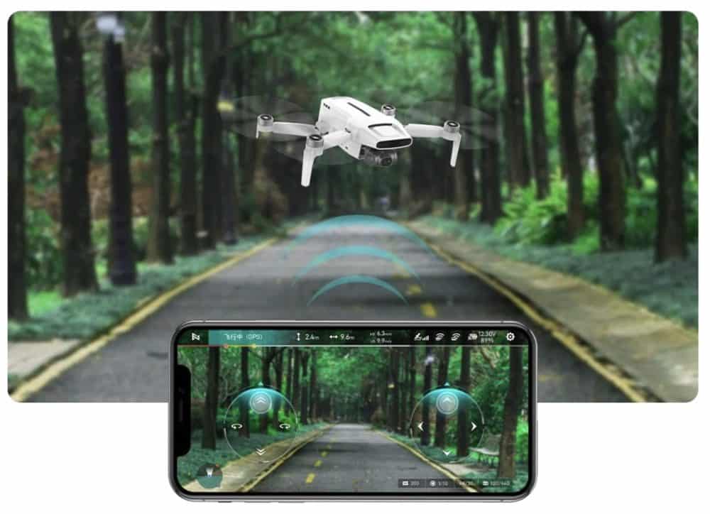 Fimi X8 Mini hovering over a forest road above a smartphone app view.