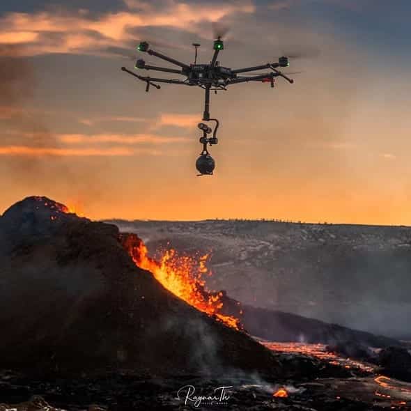 Large hexacopter carrying a 360 camera above glowing lava at sunset.