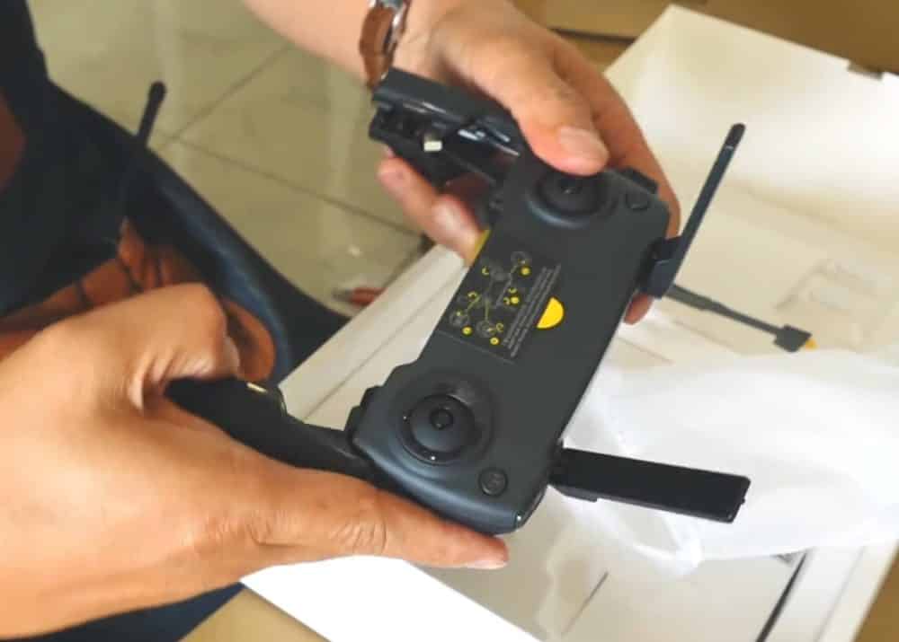 Hands unboxing the DJI Mini SE controller with its antennas folded out.