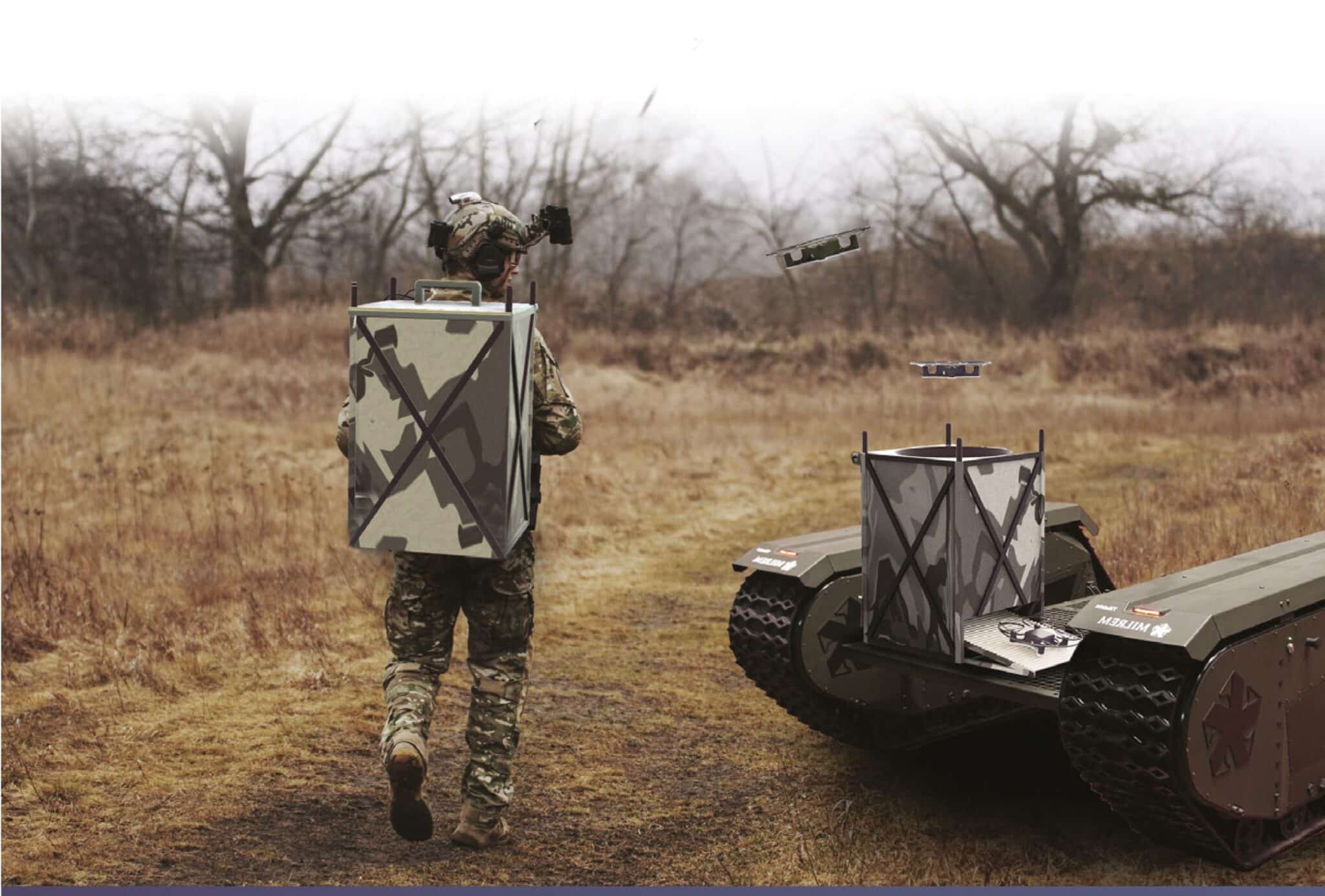Soldier with a backpack launcher walks beside a tracked SkyHive docking vehicle in a field.