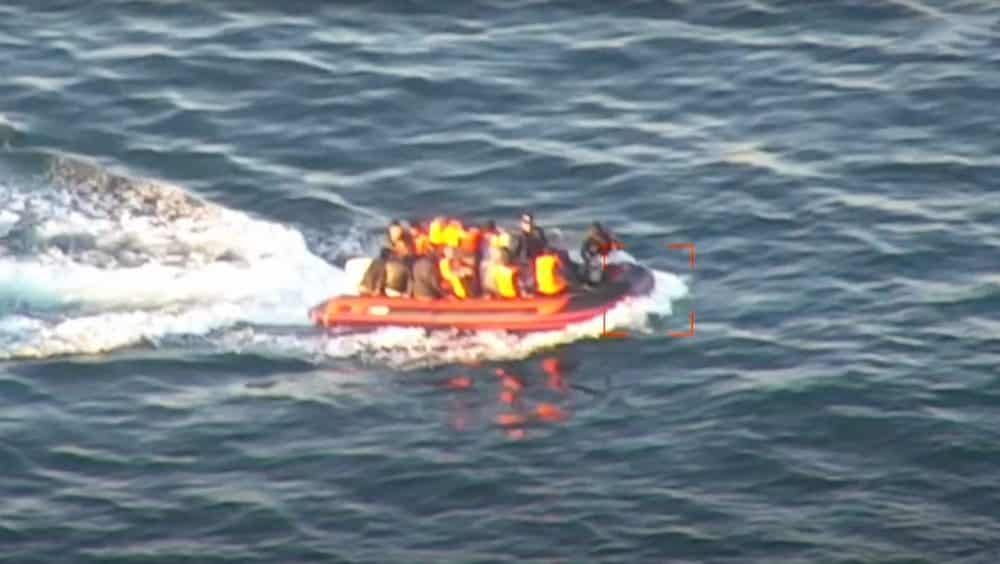 Aerial view of a crowded inflatable boat crossing open water.