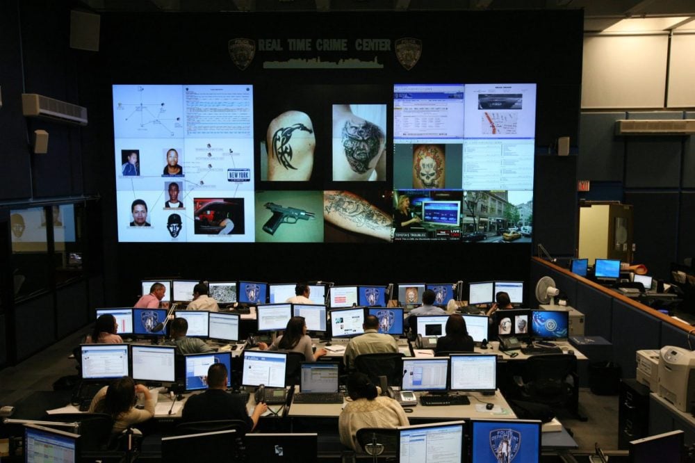Analysts at desks inside the NYPD Real Time Crime Center video wall room.