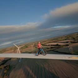 The FPV drone chases MacAskill as he balances along the turbine blade.