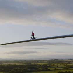 Danny MacAskill rides his bike along a wind turbine blade high above the ground.