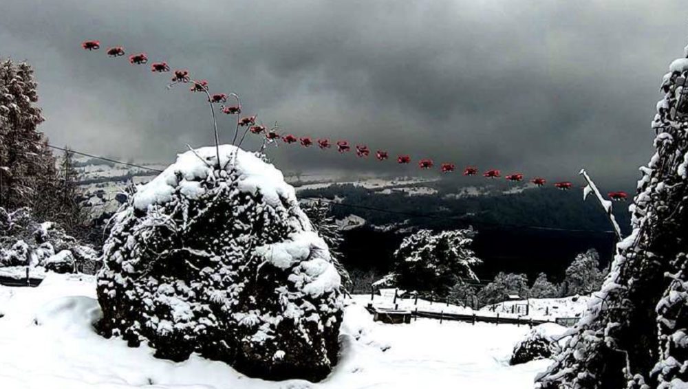Composite showing a quadrotor tracing a curved path over snow-covered terrain.
