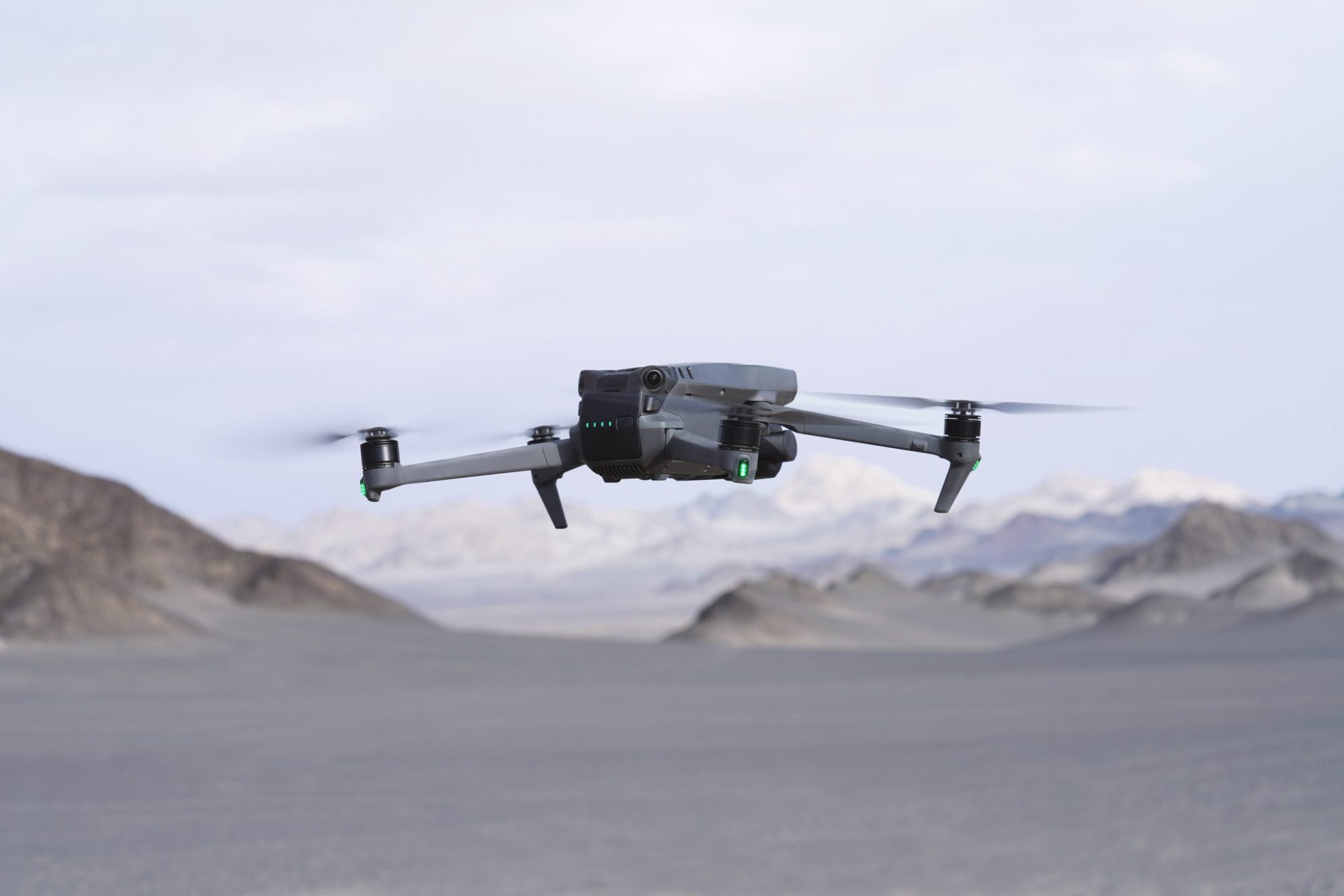 DJI Mavic 3 flying above a pale desert flat ringed by mountains.