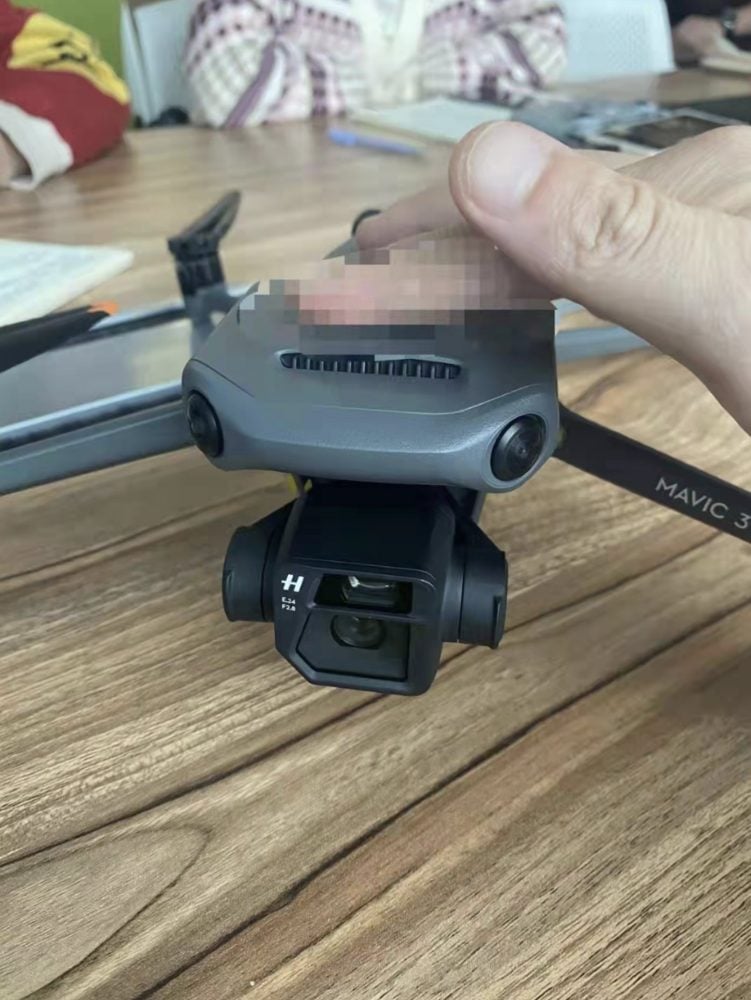 Leaked photo of a DJI Mavic 3 on a wooden table with its gimbal exposed.