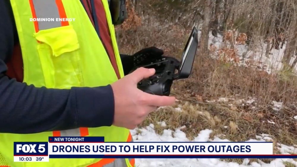 Close-up of a utility worker in a safety vest operating a drone controller.