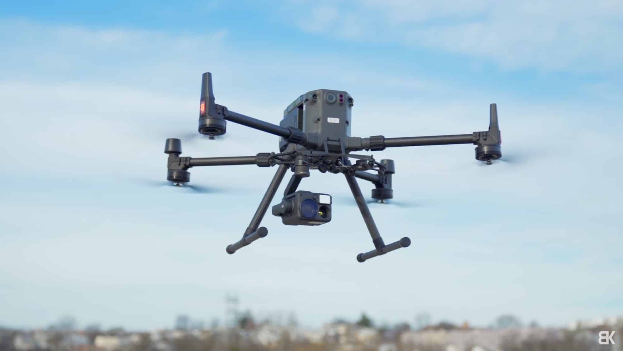 DJI Matrice 300 RTK in flight with its camera payload against blue sky.