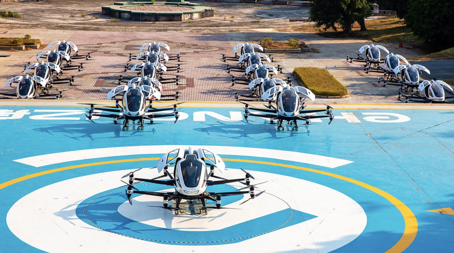 A fleet of EHang EH216 air taxis parked on a large blue helipad.