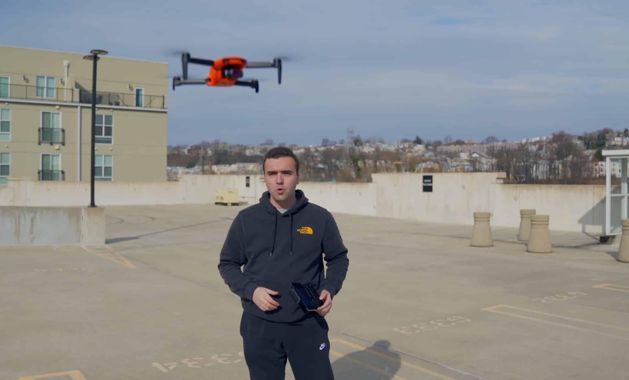 Reviewer on a rooftop deck as the orange Autel Nano+ hovers above.