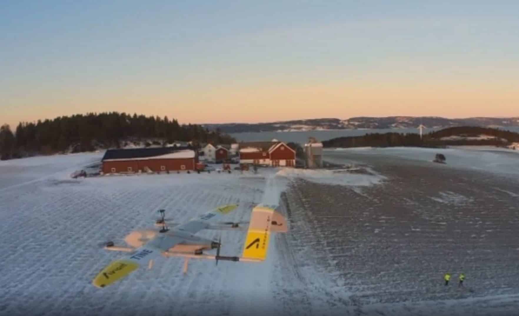 Aerial view of fixed-wing delivery drones parked at a snowy Norwegian farmstead.