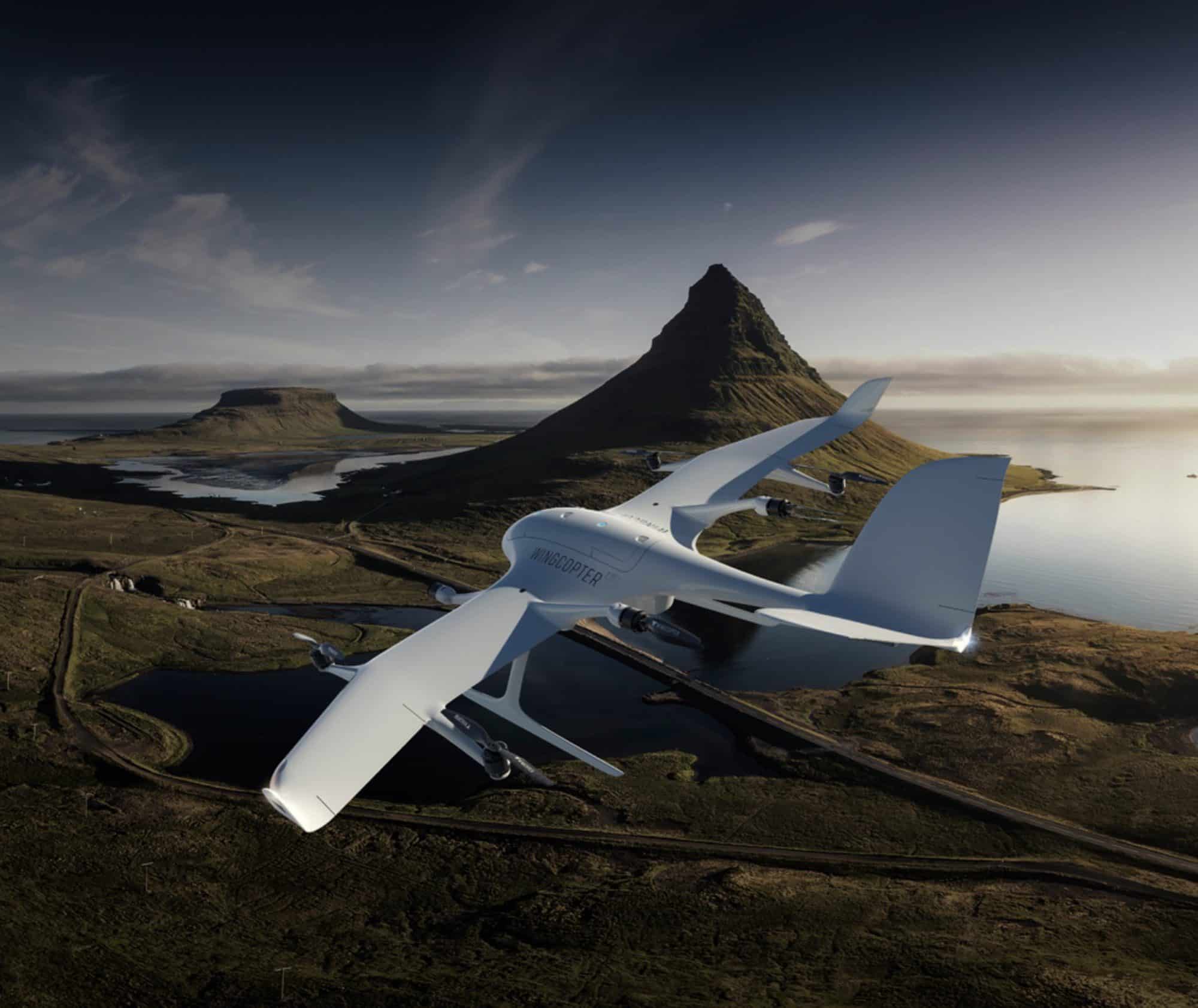 Wingcopter eVTOL drone cruising over a volcanic coastal landscape.