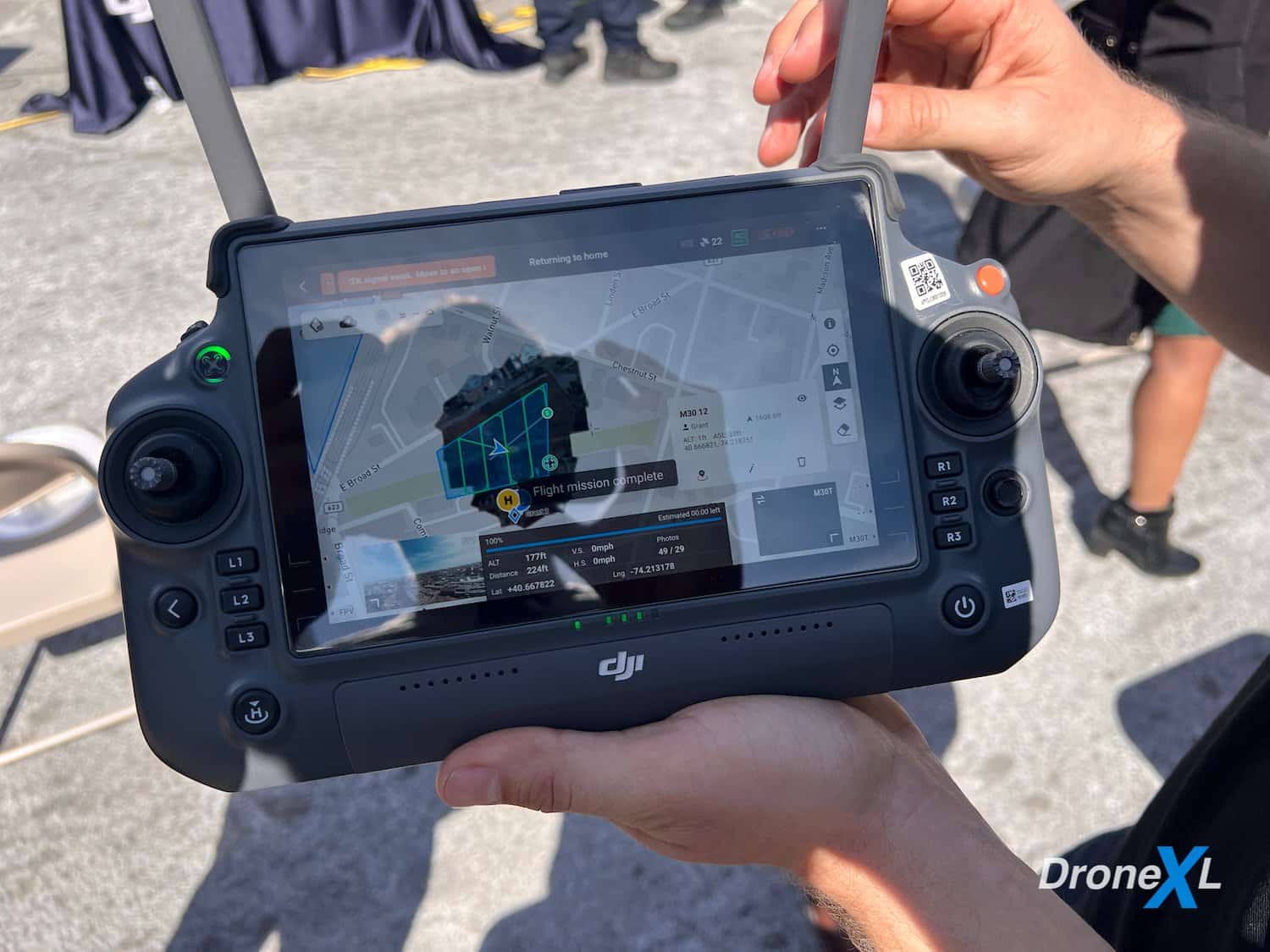Hands holding a DJI smart controller displaying a three-dimensional model on its screen.