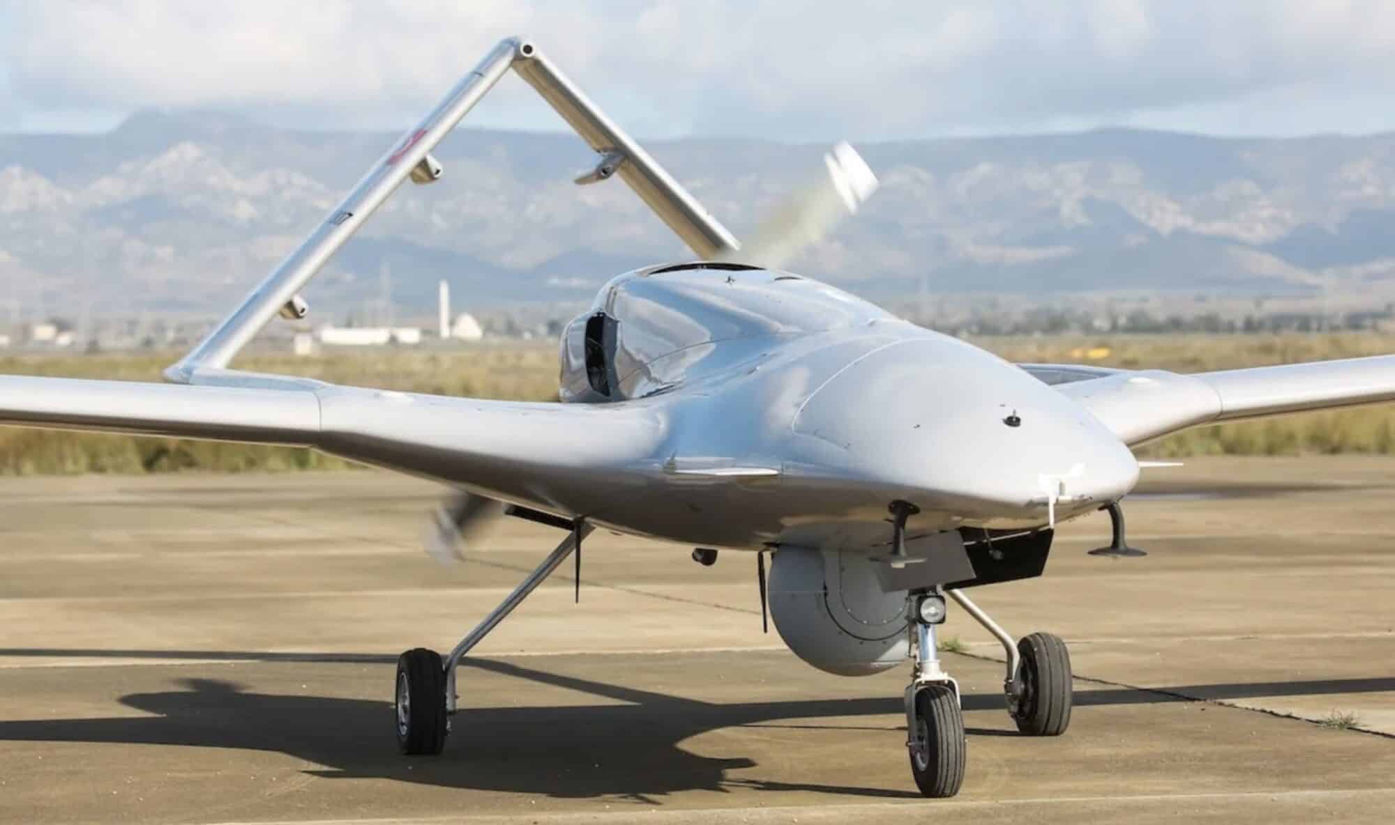 Bayraktar TB2 fixed-wing drone parked on a runway with mountains behind.