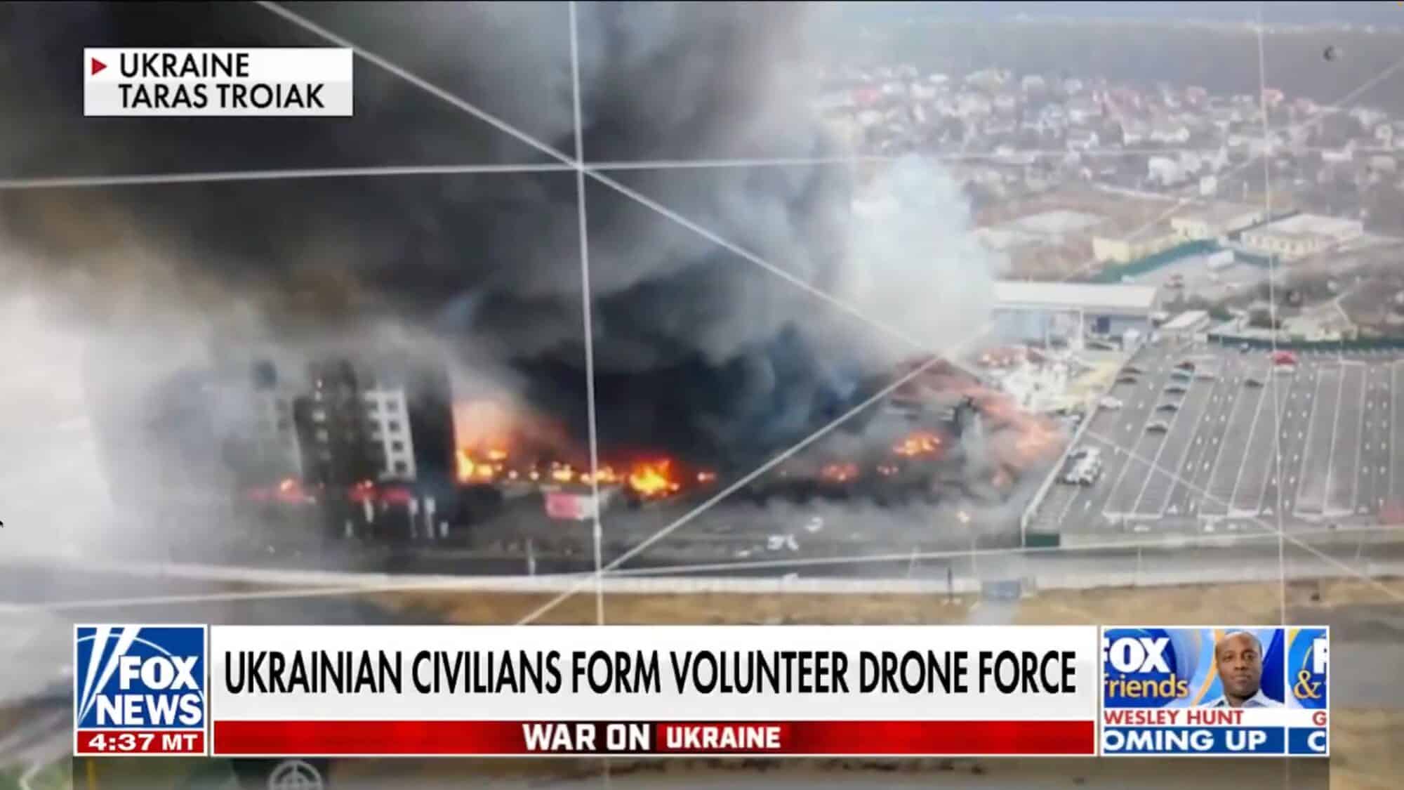 News broadcast of burning buildings under a chyron about volunteer drone crews.